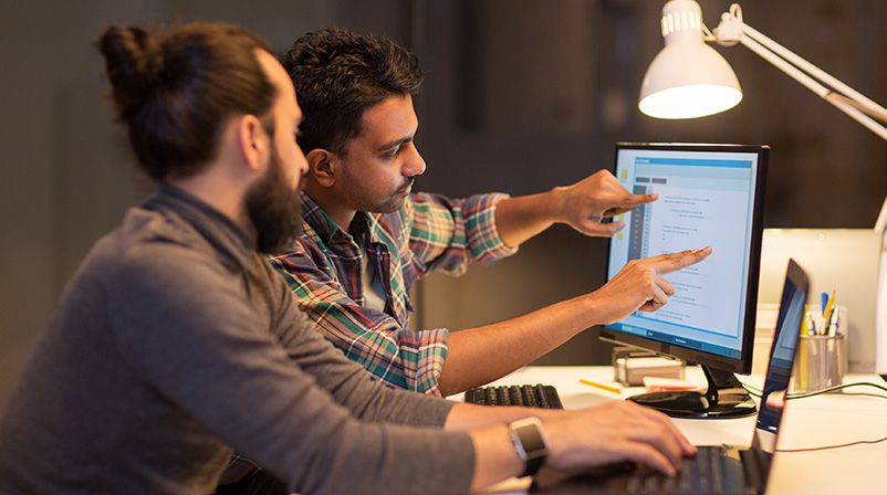 Team members analyzing work on a computer screen